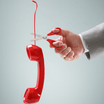 An old style phone handset dangling by its cord, and a scissor about to cut that cord. The handset is red.
