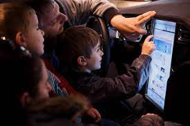 A photo of kids playing with 17" screen in tesla vehicle.