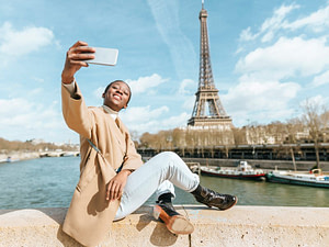 A photo of a young girl in Paris near Eiffel Tower taking a Selfie with Phone.